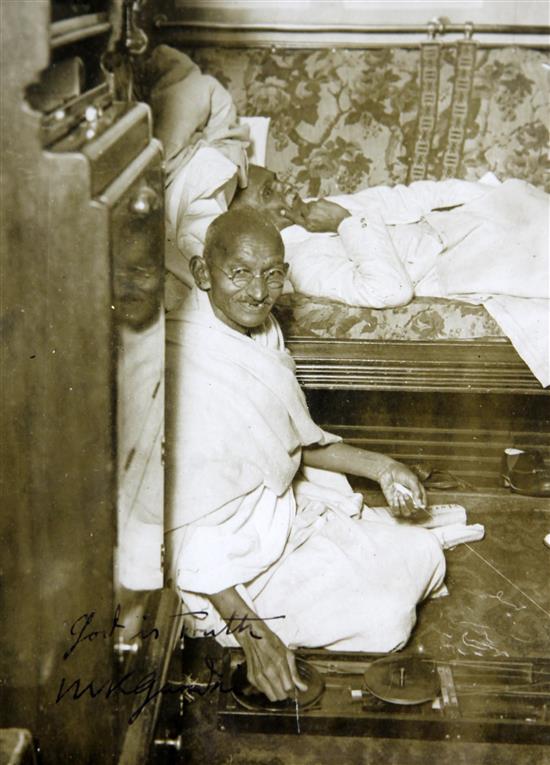 Gandhi, Mohandes Karamchand. An original press photograph of Gandhi seated spinning with a Charka, 20 x 15cms
